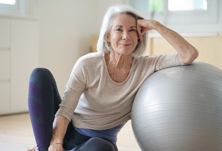 Senior woman smiling while resting against balance ball