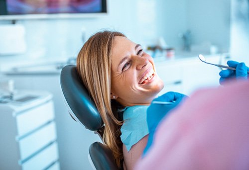 Woman in treatment chair smiling at dental hygienist