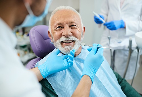 Man with white hair in green sweater about to have dental exam