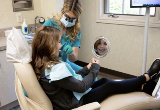 Farmington Hills dental team member showing a patient their new smile in mirror