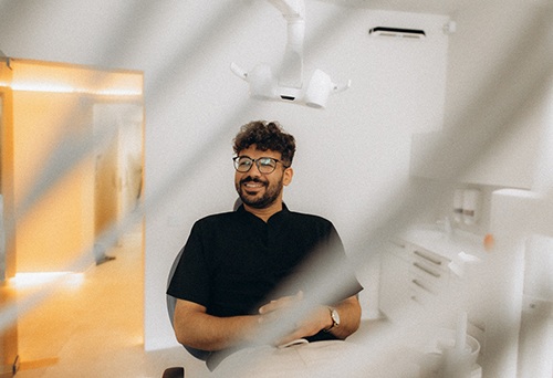 Patient with black glasses smiling in treatment chair