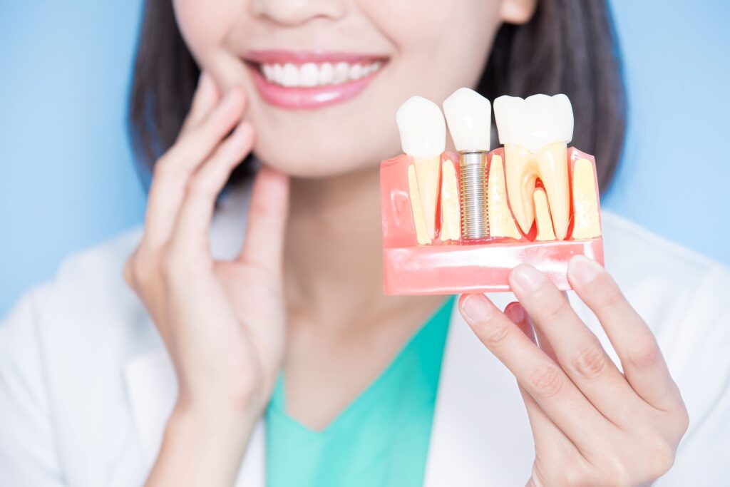 Nose-to-chest image of dentist holding sample implant and touching jaw