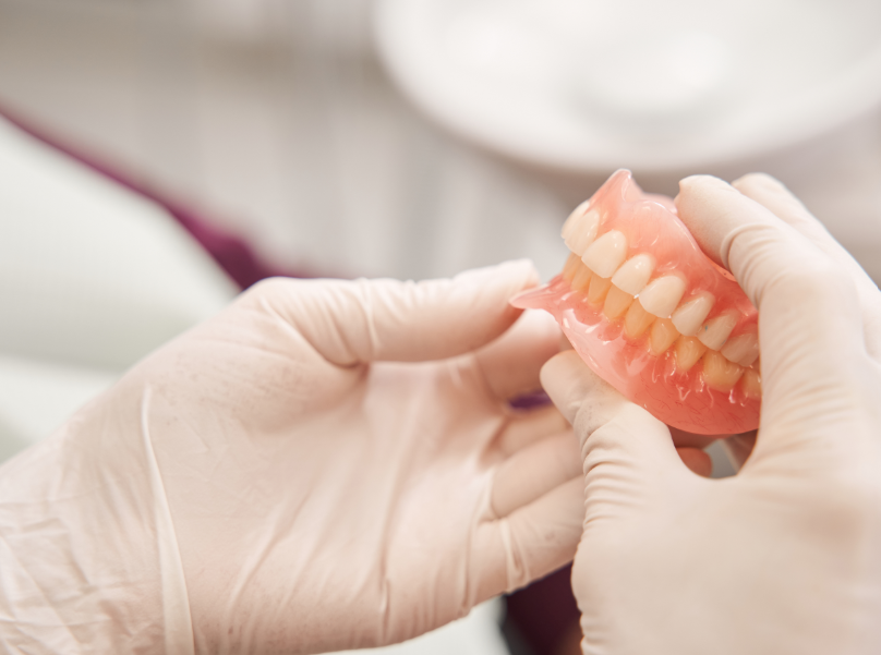 Gloved hands holding dentures